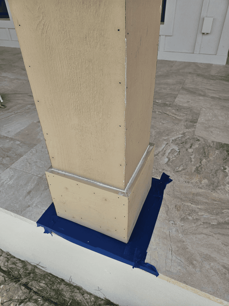 Beige porch column base with blue painter’s tape Beige porch column base with blue painter's tape